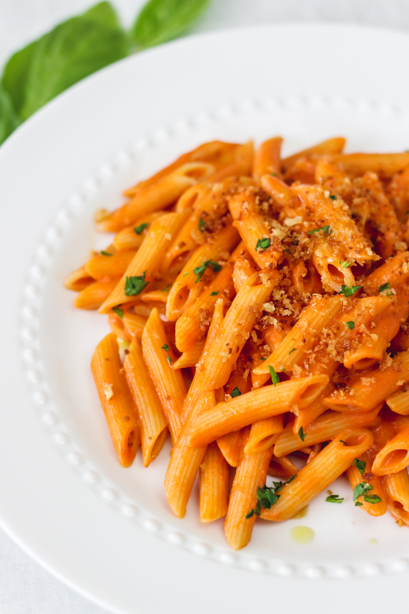 image of vegan creamy tomato pasta on a white plate. 