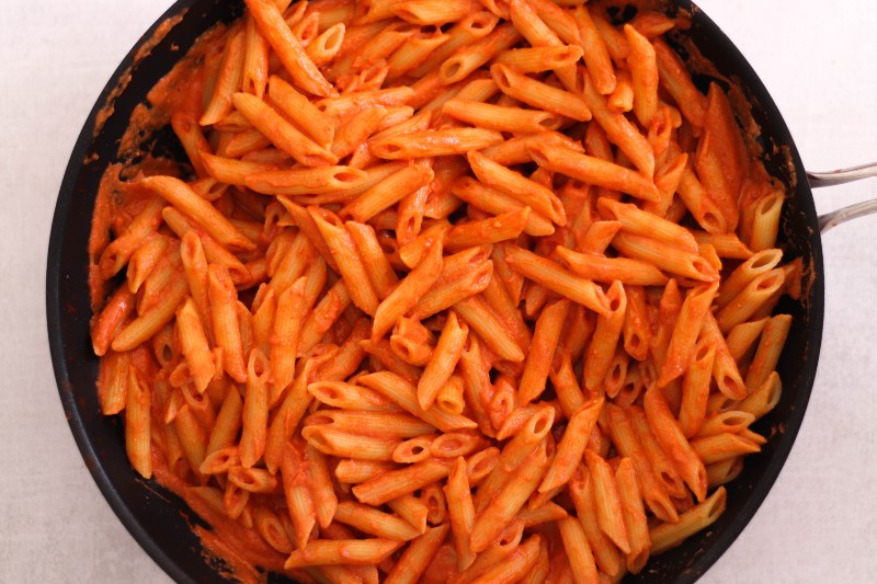image of vegan creamy tomato pasta in a skillet.