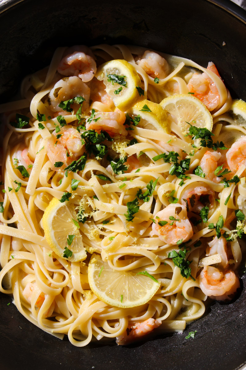 image of pasta with shrimps, lemon, and parsley in a pan