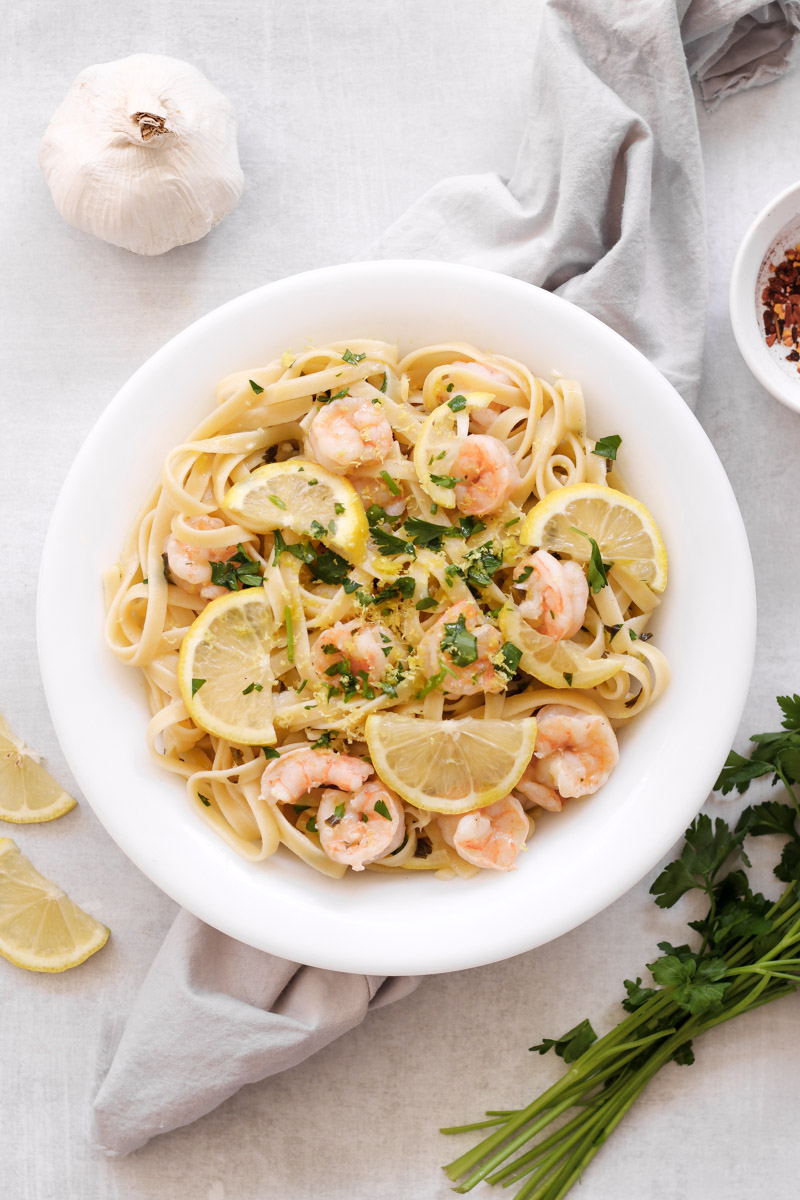 overhead image of pasta with shrimp and lemon in a white bowl