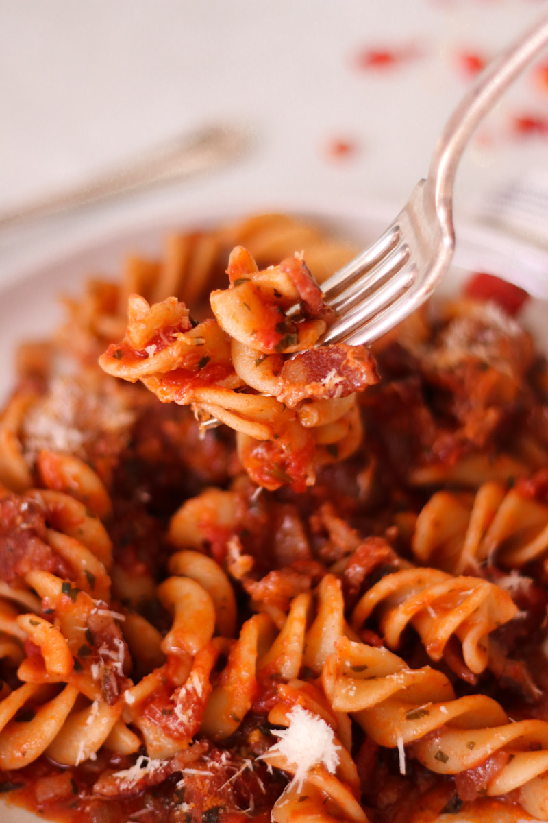 pasta amatriciana overhead shot fork taking a bite.