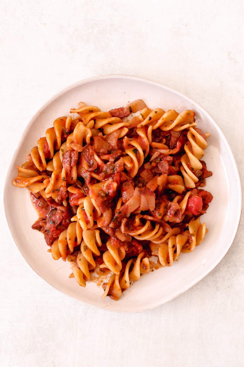 closeup image of amatriciana on white plate.