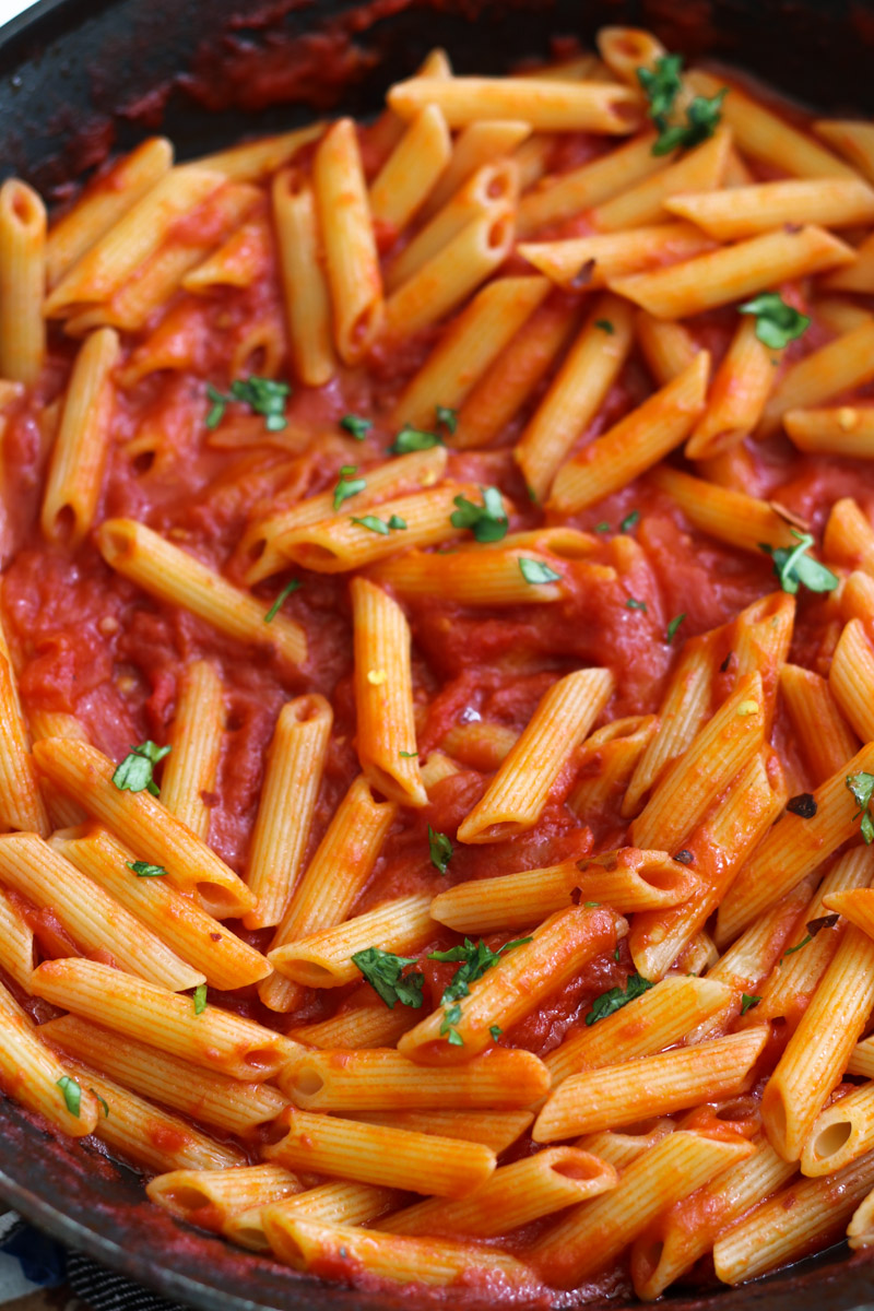 Vegan arrabbiata pasta in white bowl with parsley