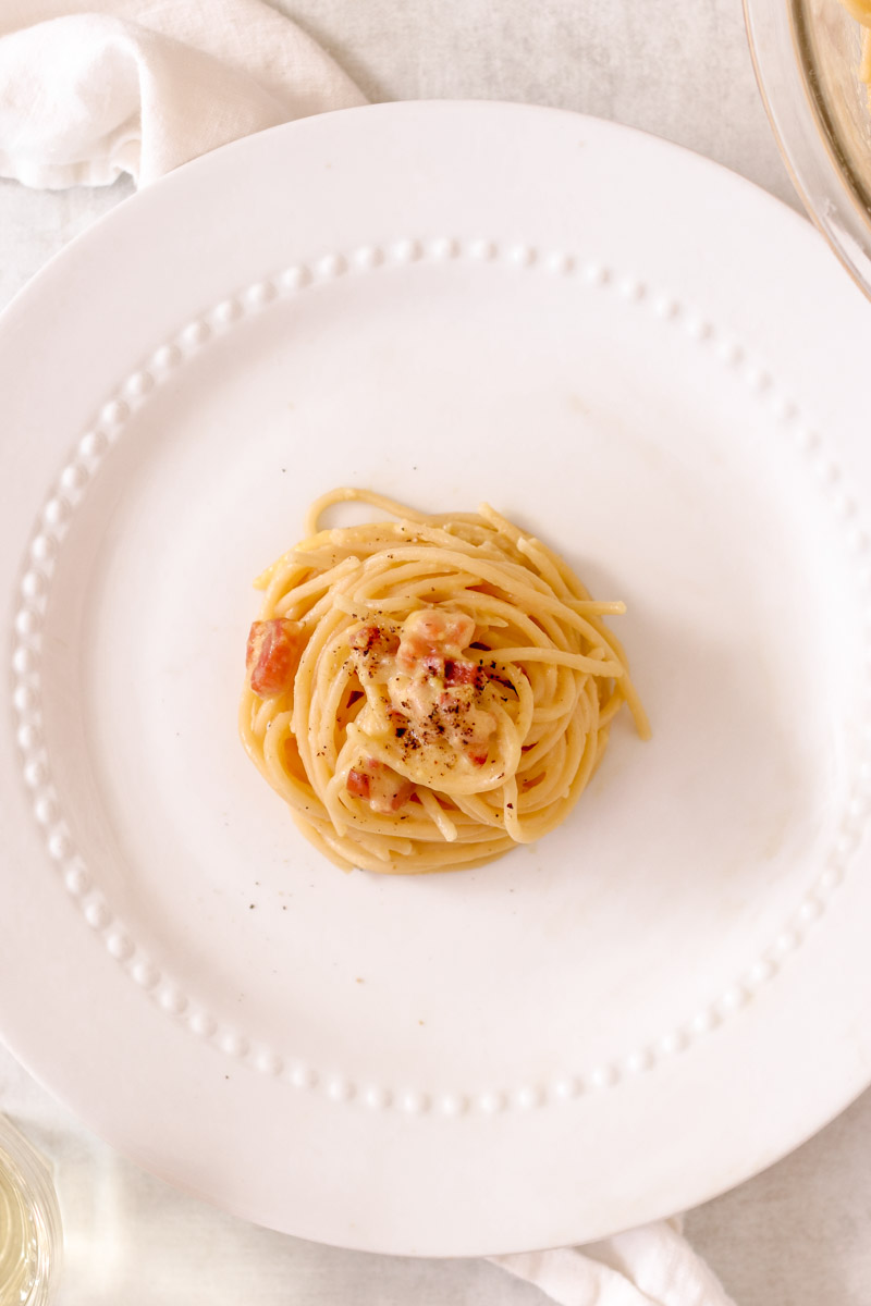 Overhead image of spaghetti carbonara on white plate.