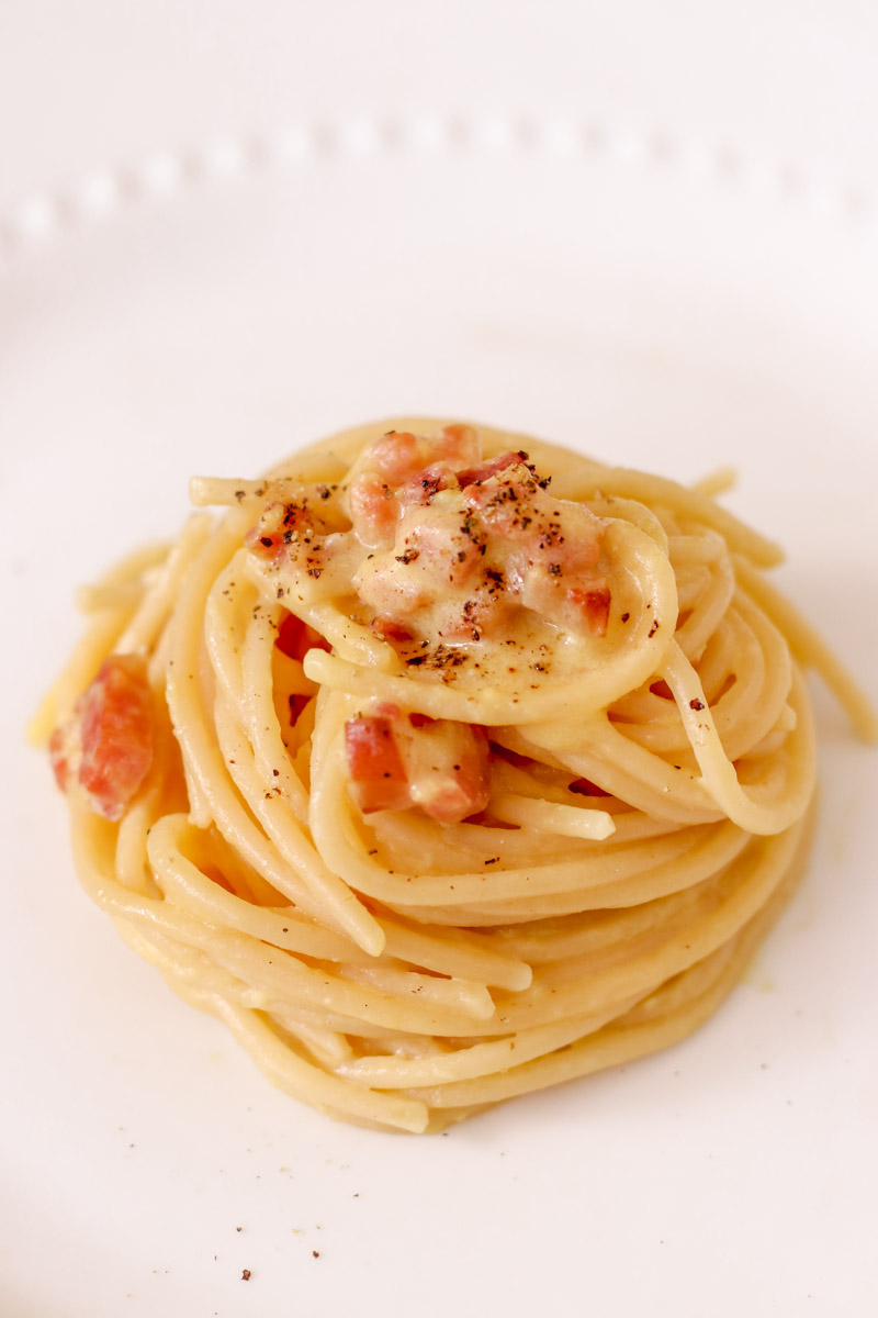 Overhead image of spaghetti carbonara on white plate.