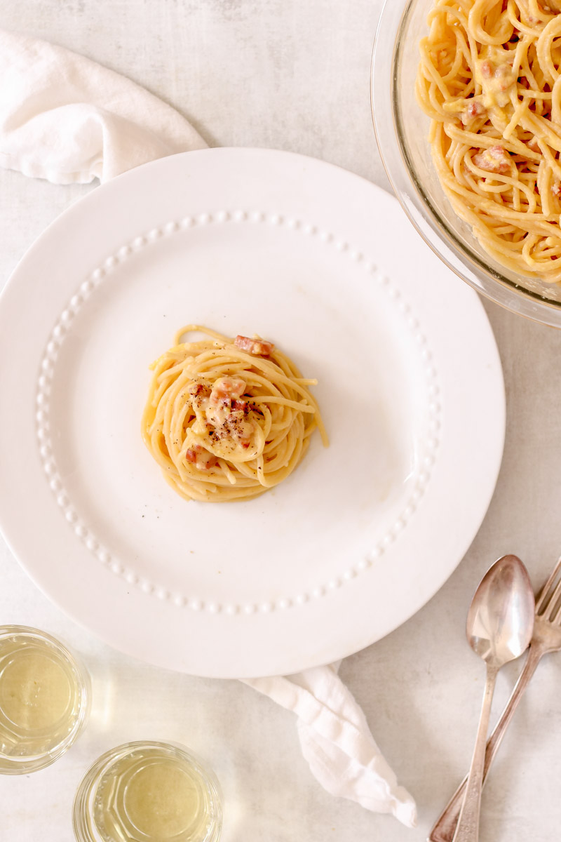 Overhead image of spaghetti carbonara on white plate.