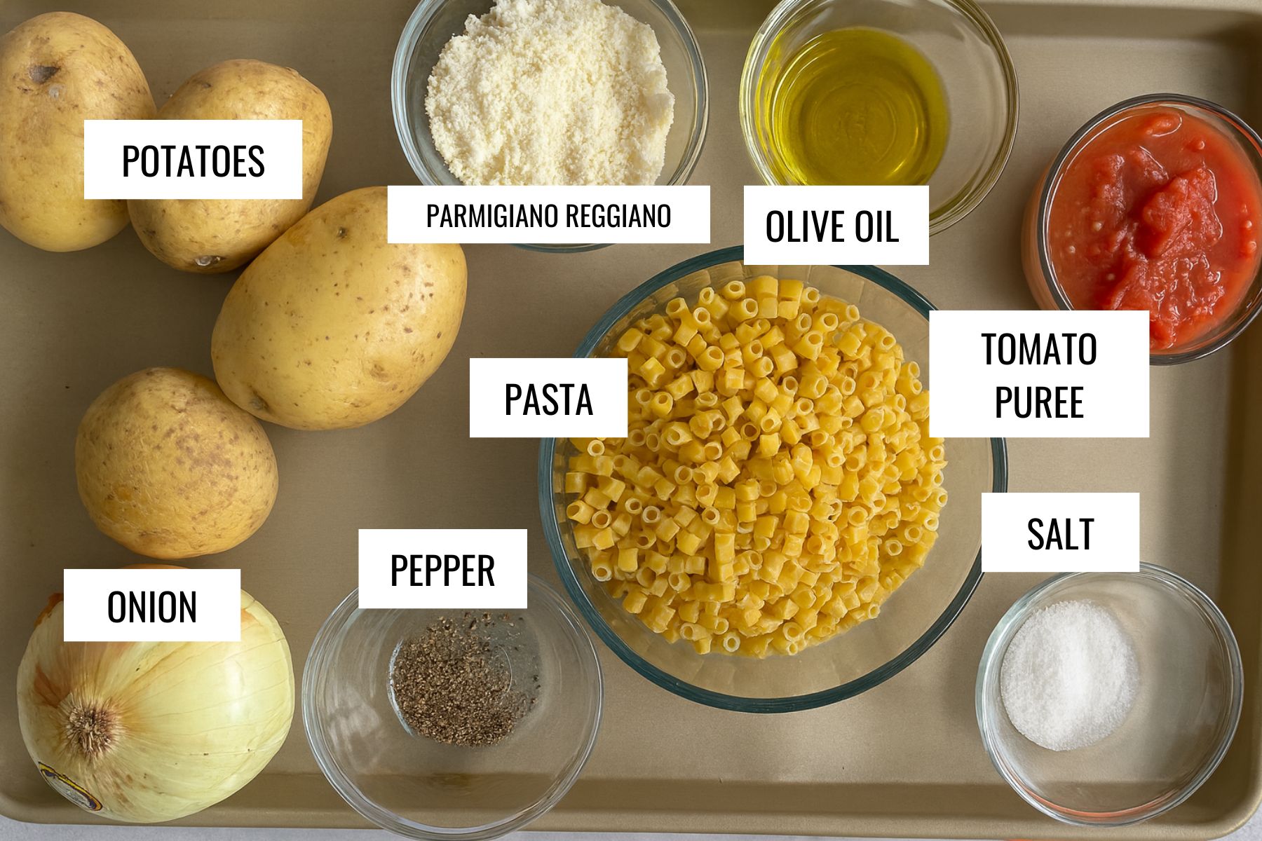 close up image of ingredinets to make pasta with potatoes in glass bowls on a baking tray. 