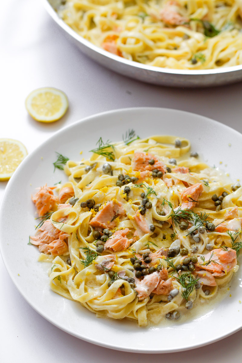 close up image of creamy salmon pasta on white plate.