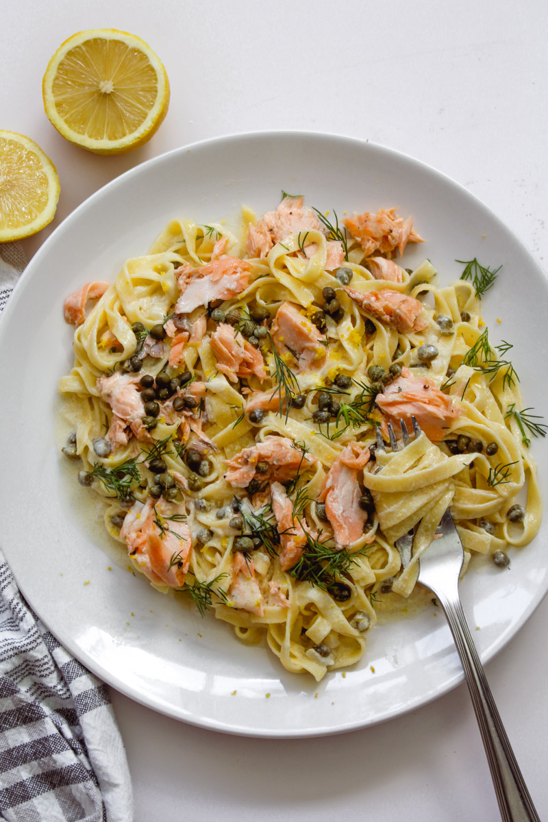 close up image of creamy salmon pasta on white plate.