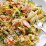 Creamy salmon pasta on white plate.
