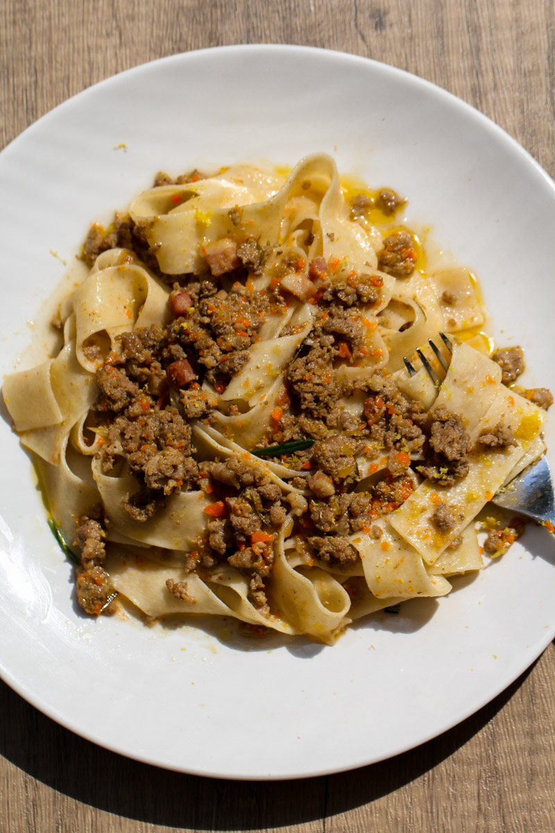 close up image of a pasta with a white ragu on a white plate and a fork. 
