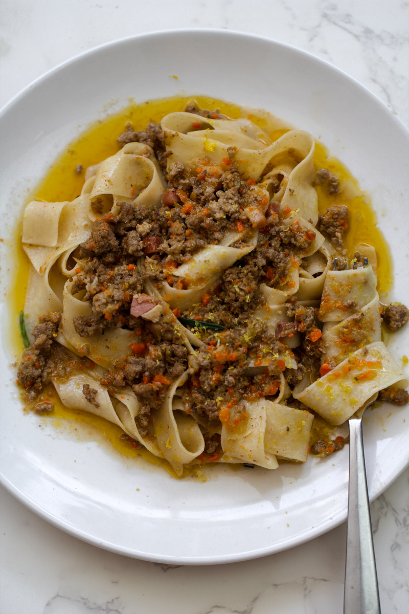 close up image of a pasta with a white ragu sauce on a white plate. 