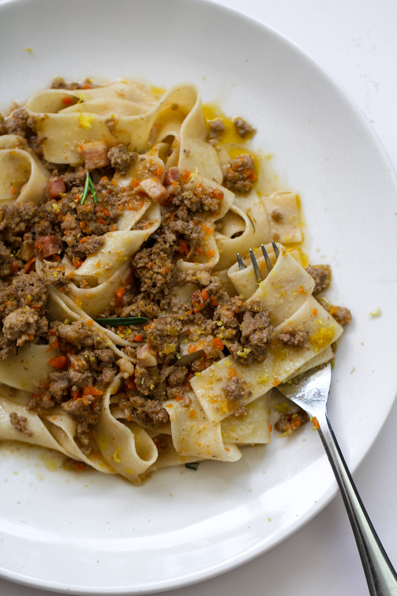 close up image of a pasta with a white ragu on a white plate and a fork. 