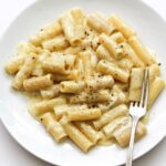 Silky garlic cream sauce coating penne pasta in a white ceramic bowl