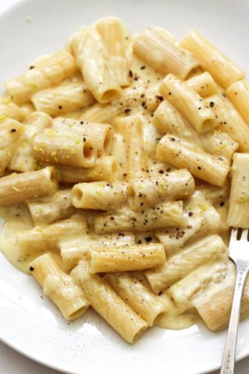 Silky garlic cream sauce coating penne pasta in a white ceramic bowl