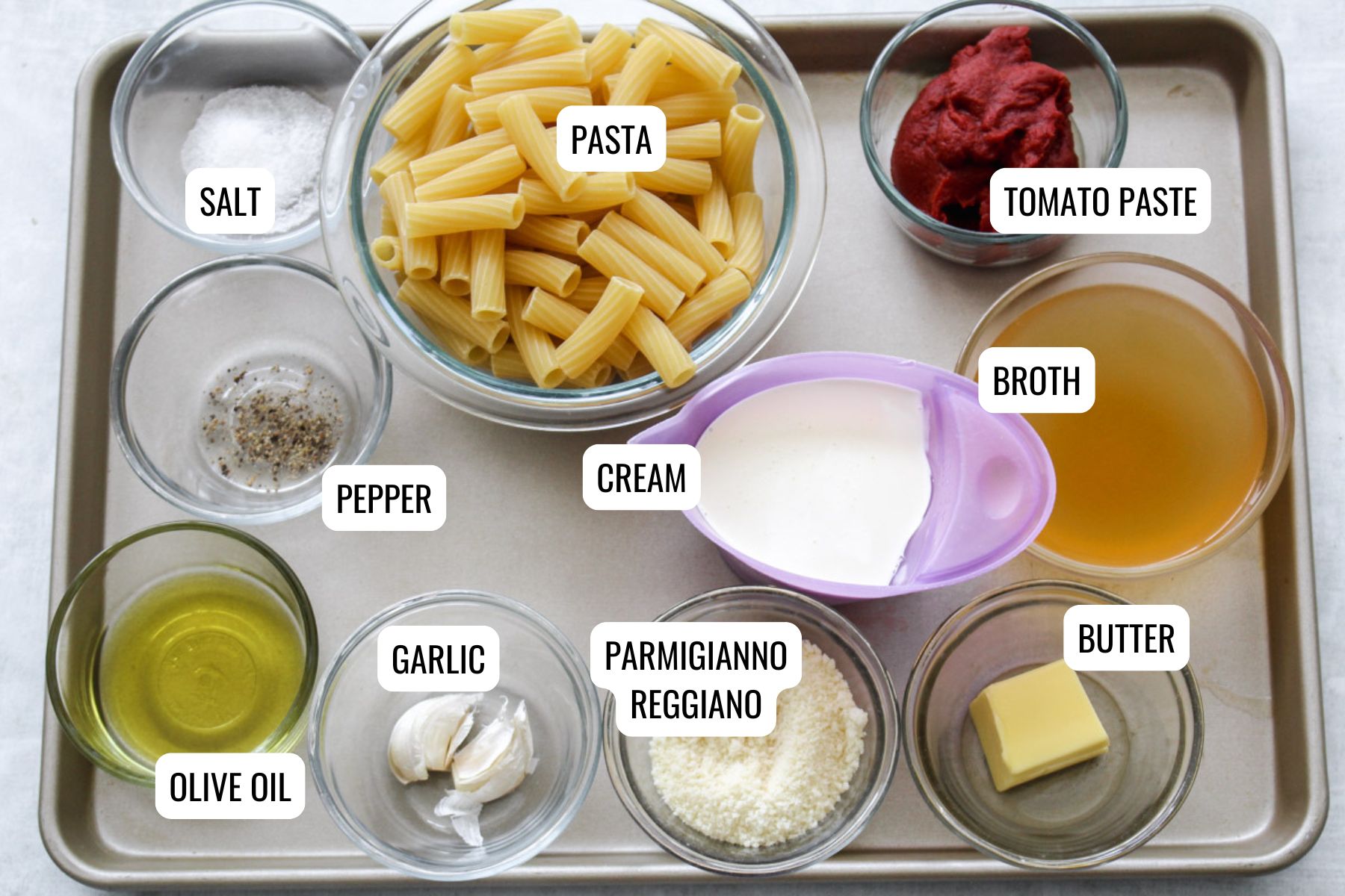 overhead image of ingredients on a baking tray to make creamy tomato pasta sauce. 