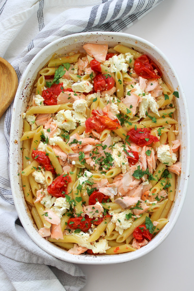 close up image of salmon feta pasta in a white casserole. 