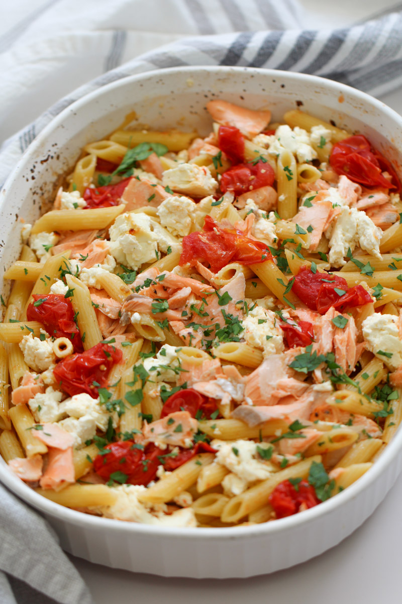 close up image of salmon feta pasta in a white casserole. 