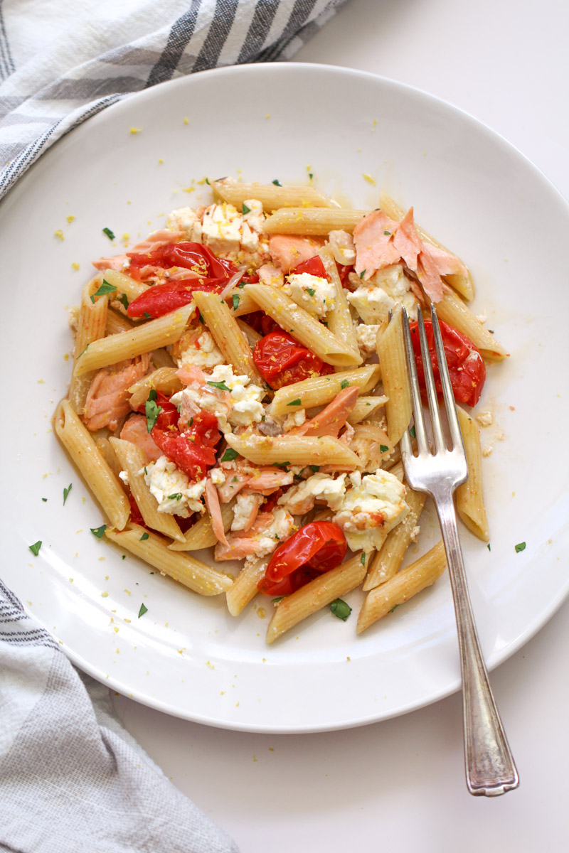 close up image of salmon feta pasta on  white plate with a fork. 