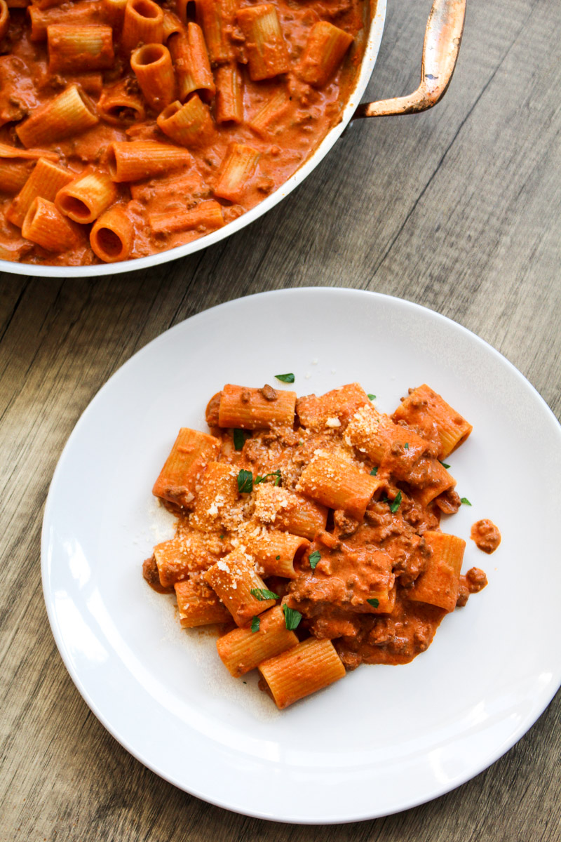 close up image of creamy beef pasta in a skillet and a white plate.