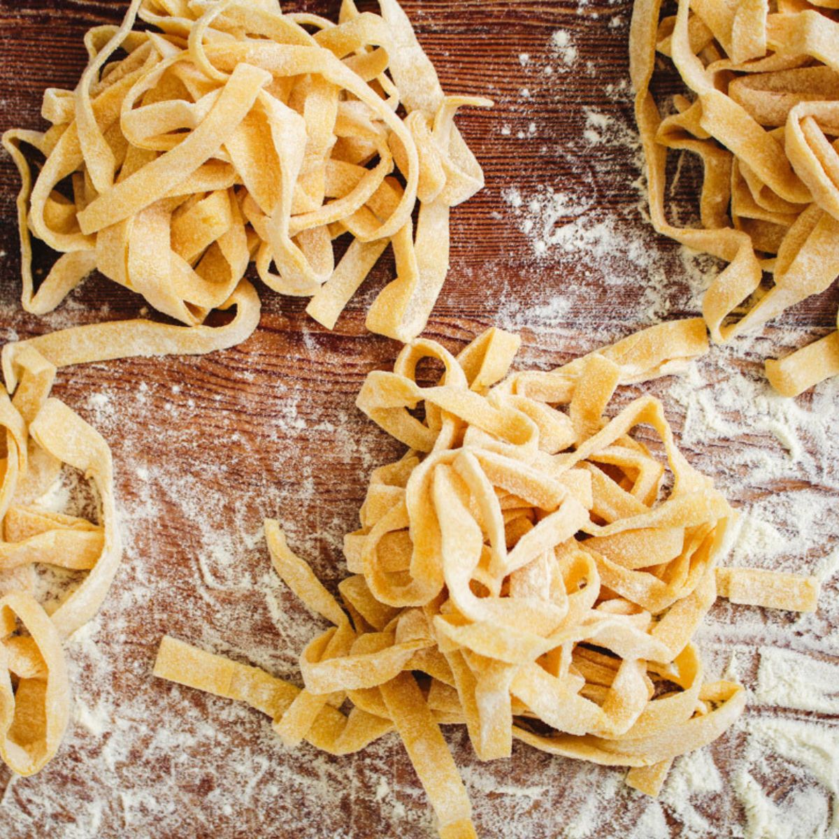 close up image of homemade tagliatelle pasta on a wooden board.