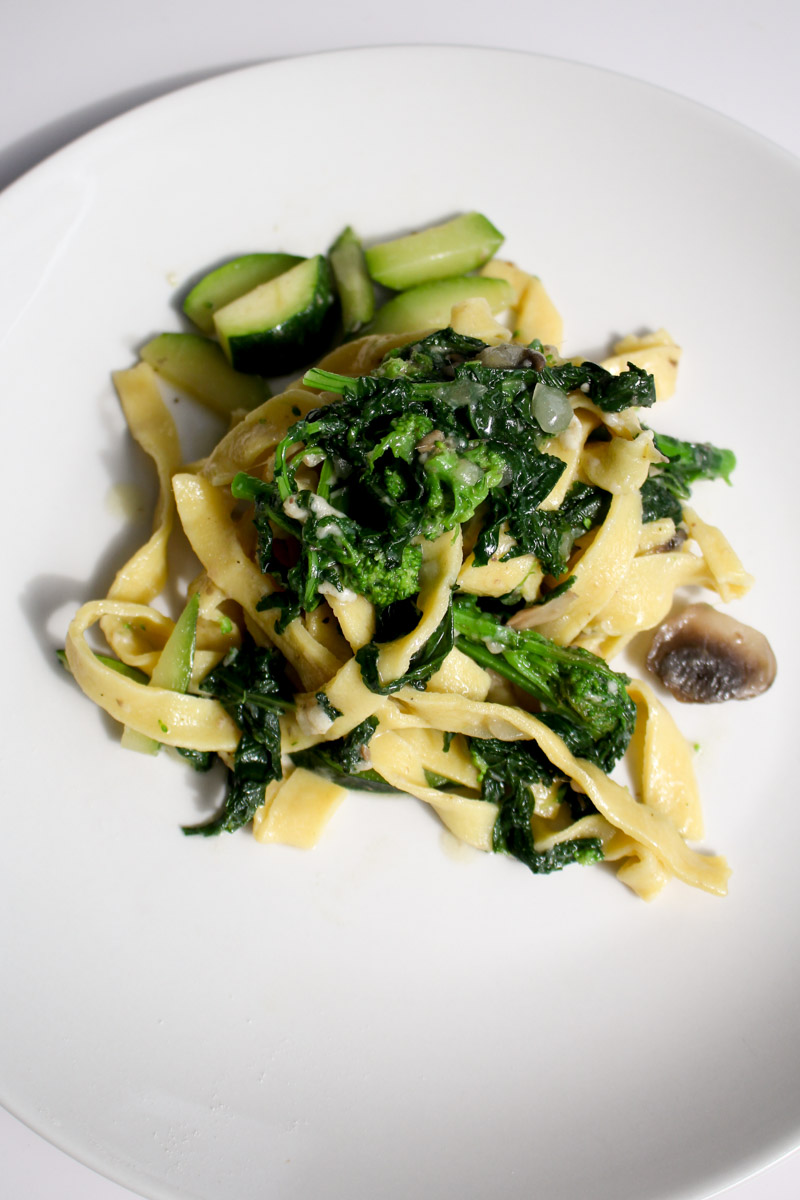 close up image of mushroom zucchini pasta on a white plate.