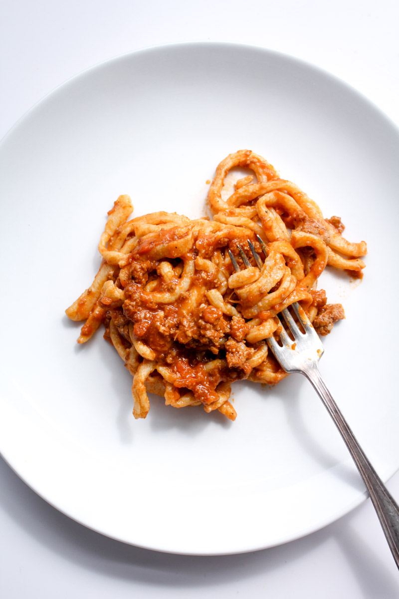 overhead image of pici with bolognese sauce. 