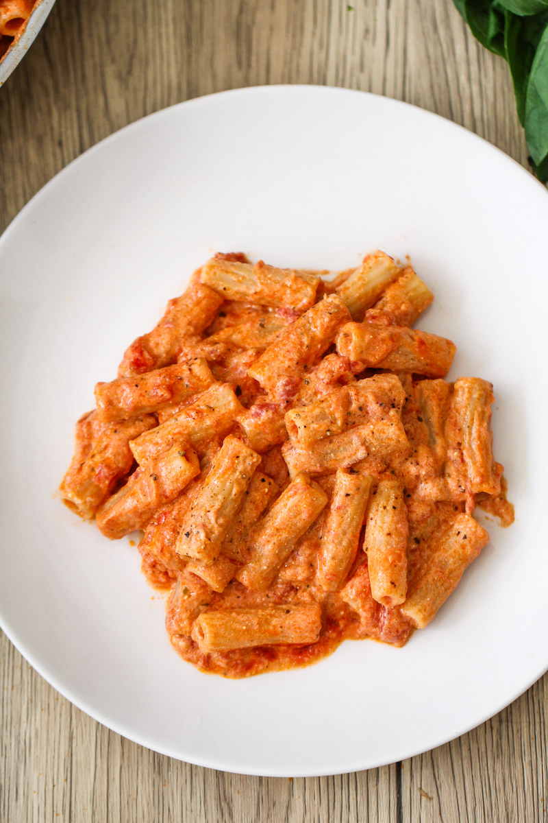overhead image of pasta with tomato ricotta sauce on a white plate. 