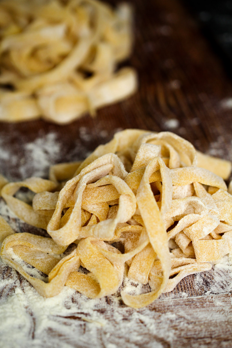 close up image of a next of tagliatelle pasta on a wooden board.