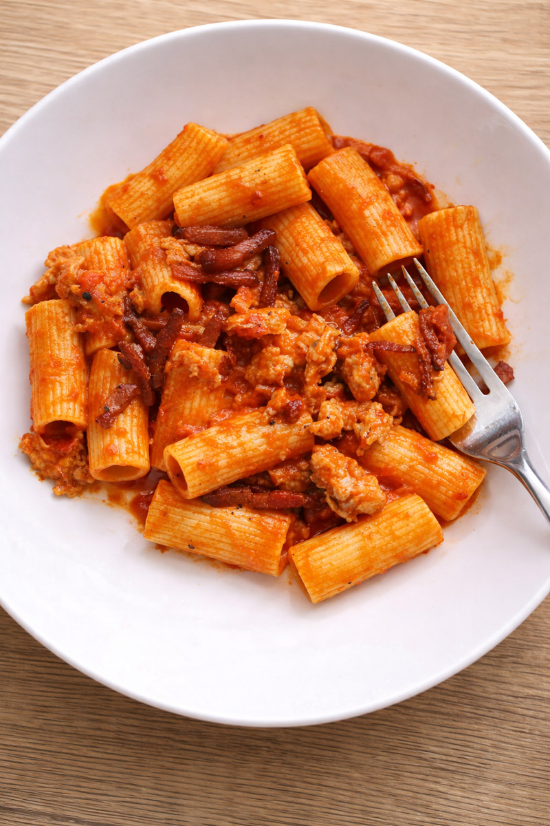 close up image of pasta alla zozzona on a white plate with a fork. 