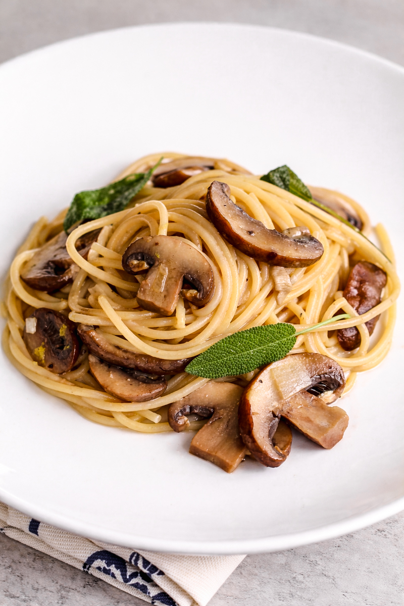 Mushroom pasta with no cream and sage on white dish.