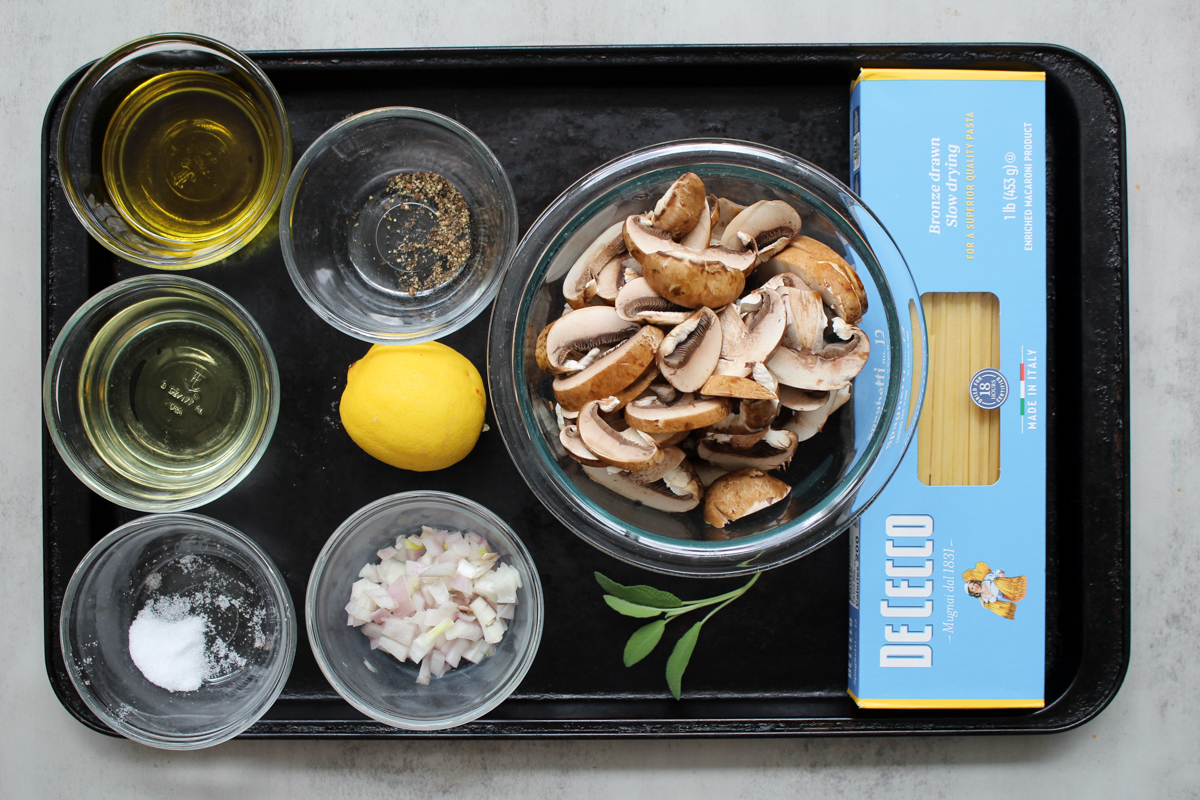 image of igredients for easy mushroom pasta without cream arranged in glass bowls on a baking tray.