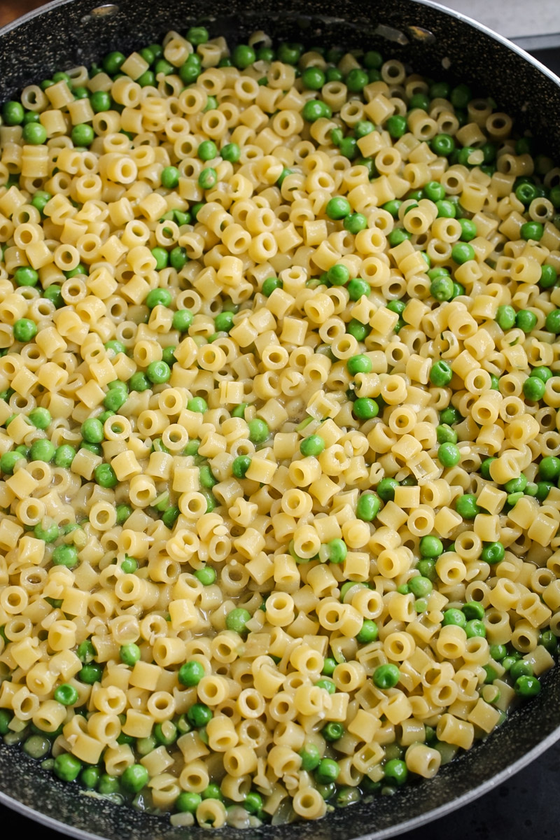 close up image of pasta and peas cooking in a skillet. 